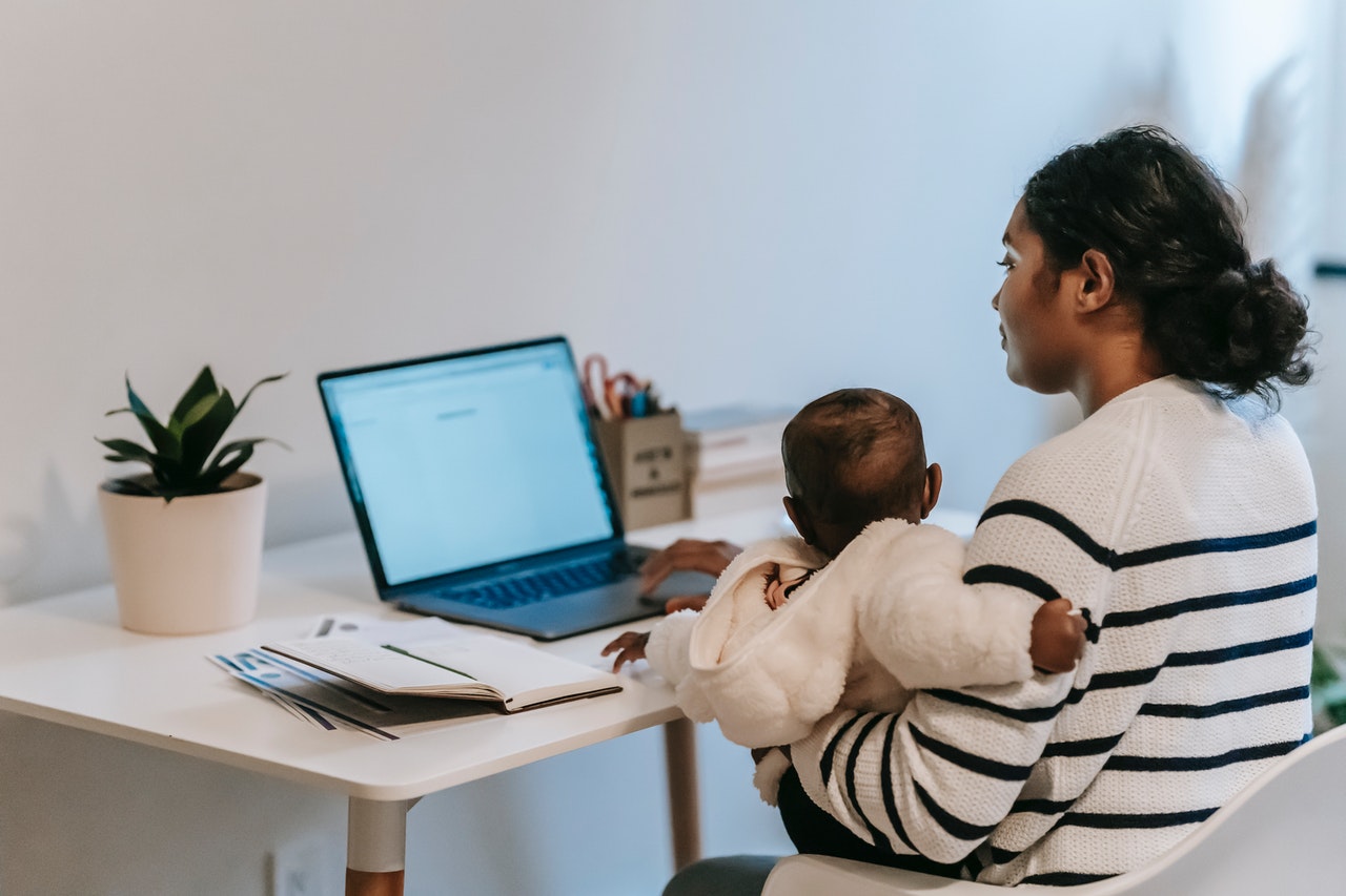 a woman completing an online form while holding a baby