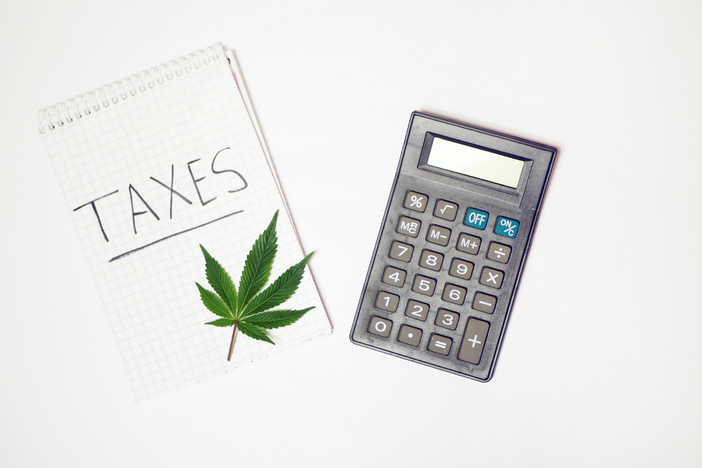 A calculator and a spiral notebook that says "Taxes," and a cannabis leaf
