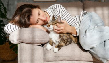 Young woman cuddling her cat at home on her couch