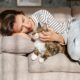 Young woman cuddling her cat at home on her couch