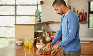 A man cutting up fruit to eat, enjoying a nutritous meal