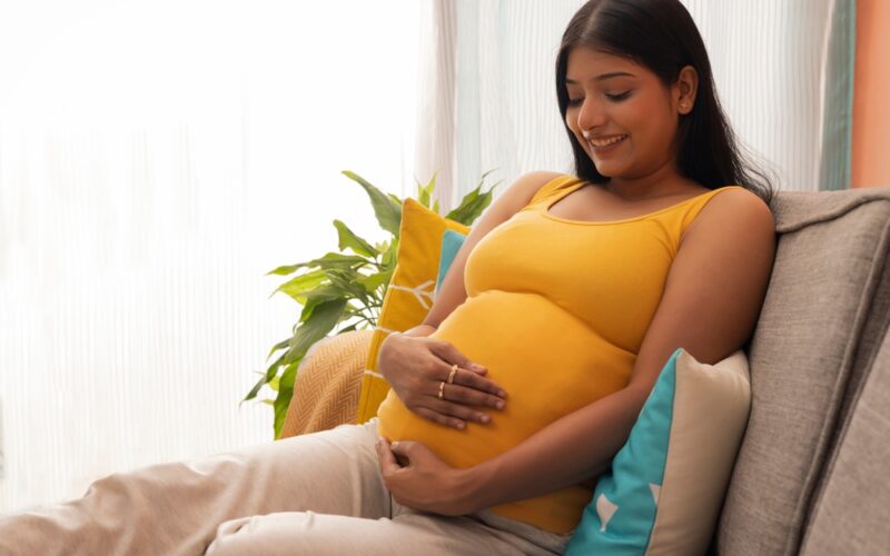 Happy Pregnant woman touching her belly and smiling