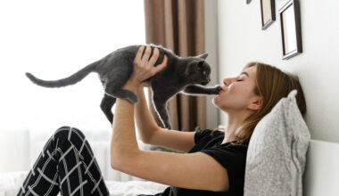 Woman playing with her Emotional Support Cat in her bed