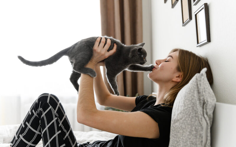 Woman playing with her Emotional Support Cat in her bed