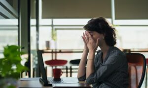 Woman sitting at her laptop dealing with fatigue