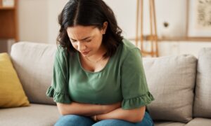 Woman sitting on her couch dealing with nausea