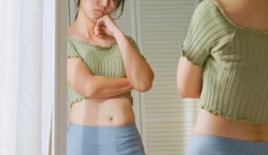 Woman standing in front of mirror unhappy with her weight