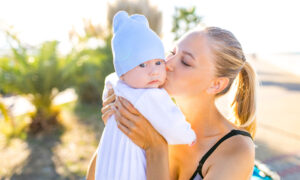 Woman holding and kissing her baby while enjoying outdoors