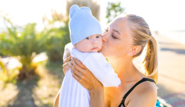 Woman holding and kissing her baby while enjoying outdoors