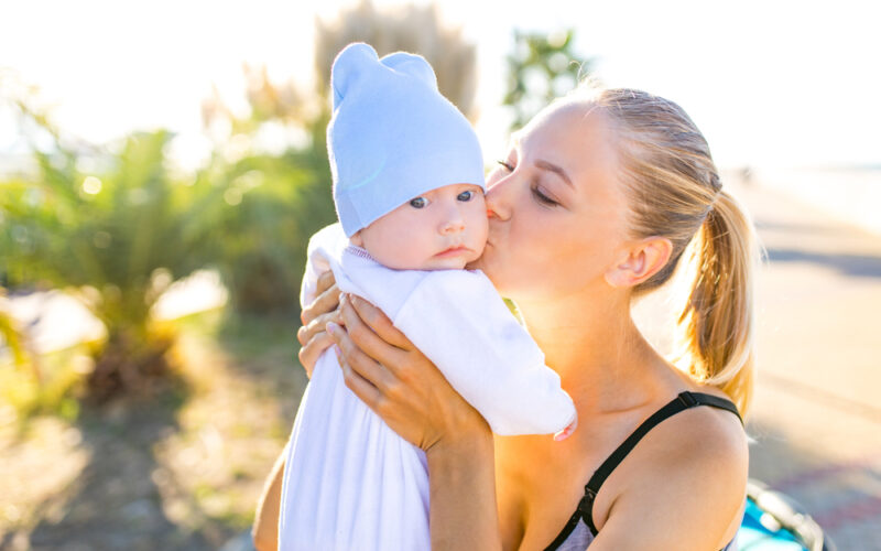 Woman holding and kissing her baby while enjoying outdoors