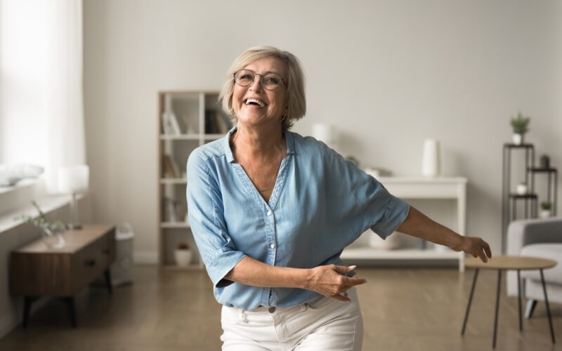 Happy older woman energized and dancing in her home