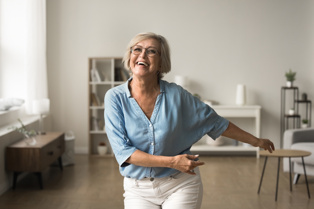 Happy older woman energized and dancing in her home