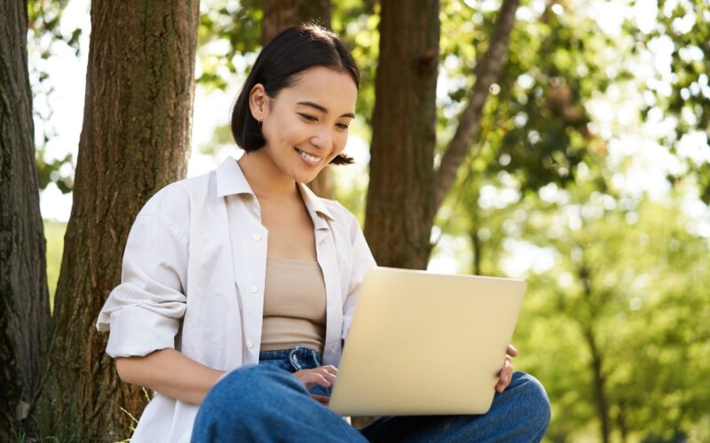 Young happy woman on laptop in the park