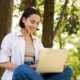 Young happy woman on laptop in the park