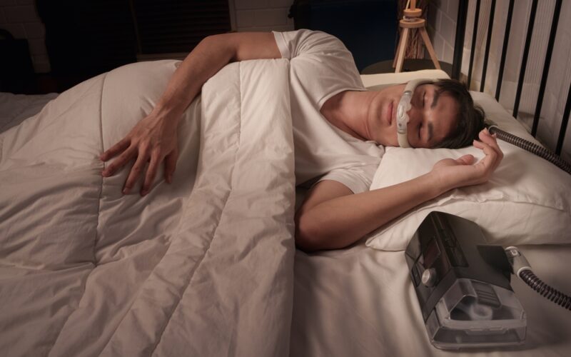 Young man peacefully asleep wearing a sleep apnea machine