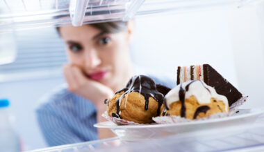 Hungry young woman looking at dessert in the fridge