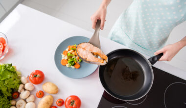 High angle view of a woman plating salmon with vegetables