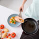 High angle view of a woman plating salmon with vegetables