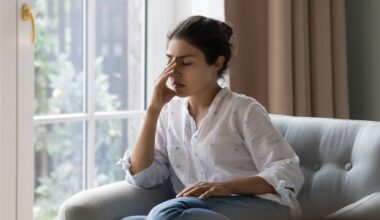 Young woman dealing with headache while sitting on couch