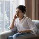Young woman dealing with headache while sitting on couch