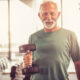 Smiling older man in the gym holding a dumbbell