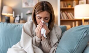 Young woman blowing her nose and dealing with sickness