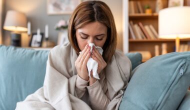 Young woman blowing her nose and dealing with sickness