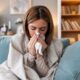 Young woman blowing her nose and dealing with sickness