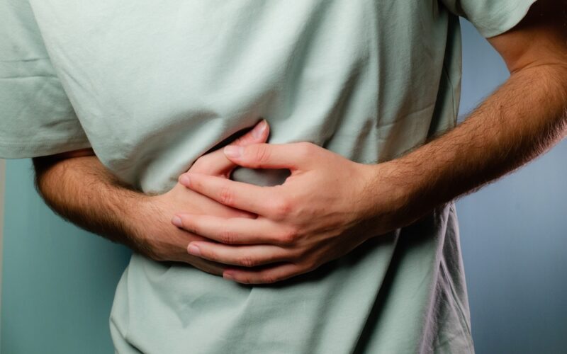 Young man holding his stomach in pain