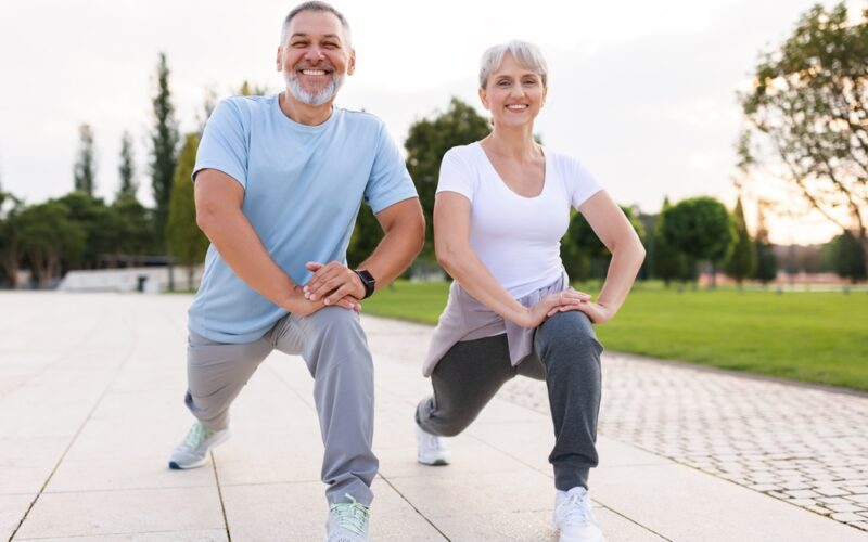 Two older people stretching for morning exercise, happy and energized