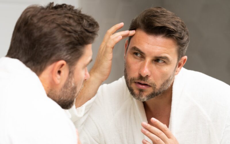 Man fixing his hair in the bathroom mirror