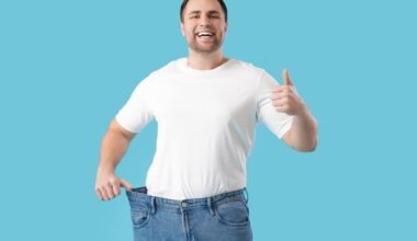 Young man happy as he shows weight loss with his old pants
