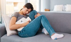 Woman laying on couch dealing with stomach pain