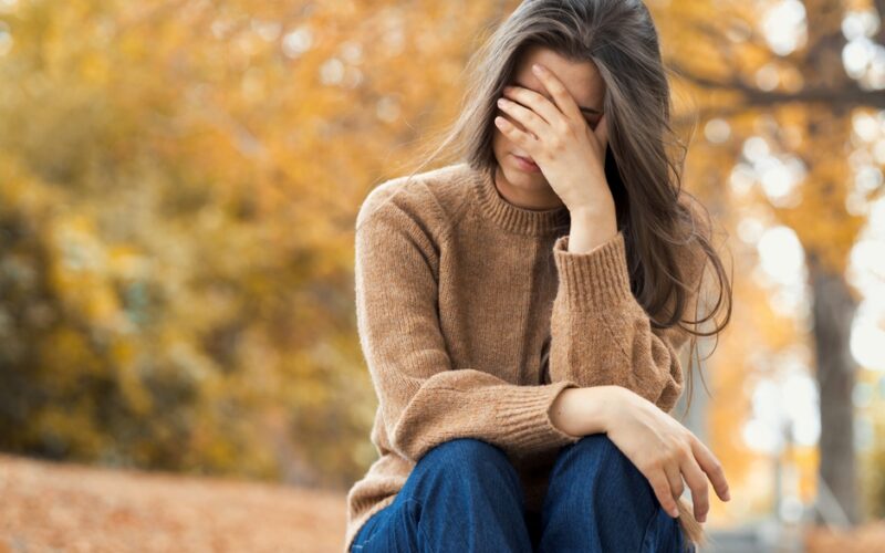 Woman sitting in park unhappy, dealing with depression