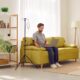 Man receiving IV therapy while sitting on couch with his laptop