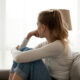 Side view of unhappy woman looking into the distance, sitting on the couch