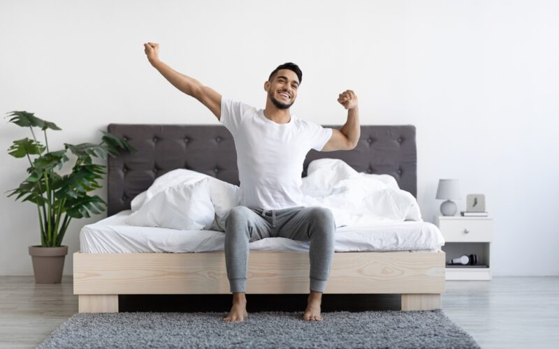 Happy young man waking up after having a good night of sleep