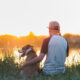 Man hugging his dog while enjoying the sunset