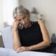 Unhappy middle aged woman sitting on couch