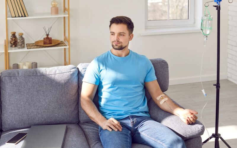 Man sitting on couch receiving IV therapy