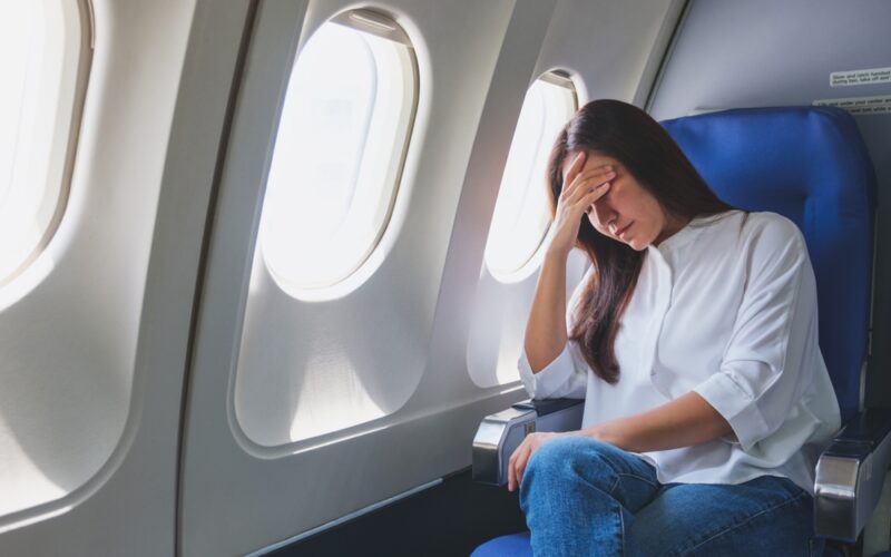Woman feeling sick and tired while sitting on airplane