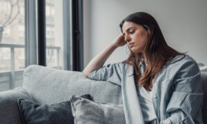 Up close shot of sad woman sitting on couch