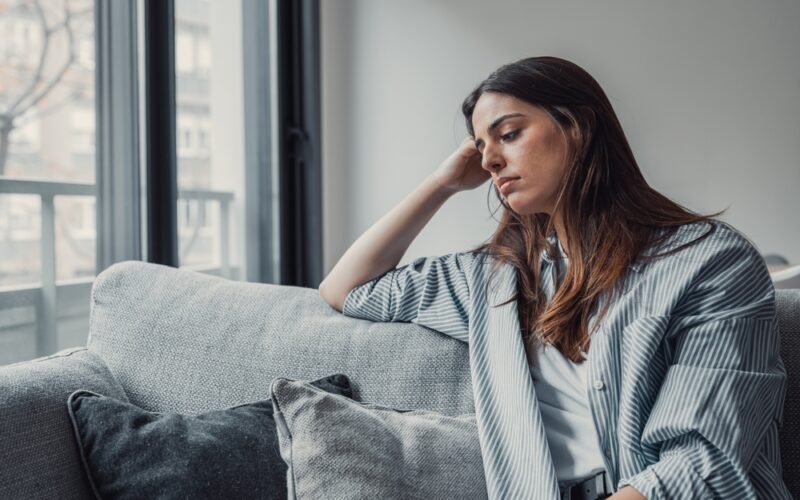 Up close shot of sad woman sitting on couch