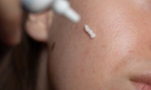 Close up of woman applying prescription cream to face