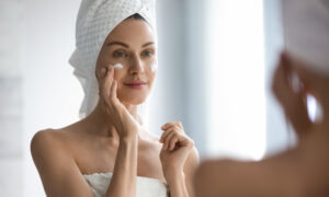Woman applying face cream in the mirror