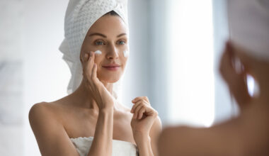 Woman applying face cream in the mirror