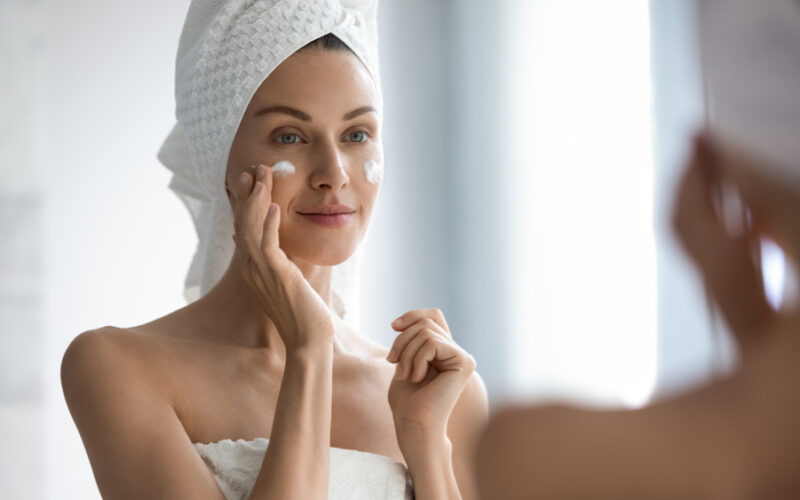Woman applying face cream in the mirror