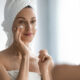Woman applying face cream in the mirror