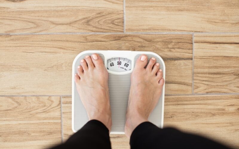 Close up of someone standing on a scale and weighing themselves