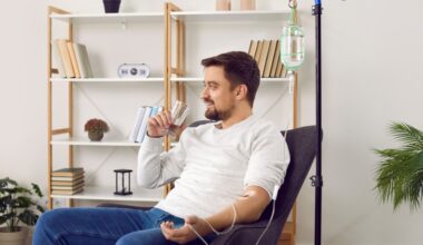 Man sitting down and receiving hydration IV therapy while drinking a glass of water